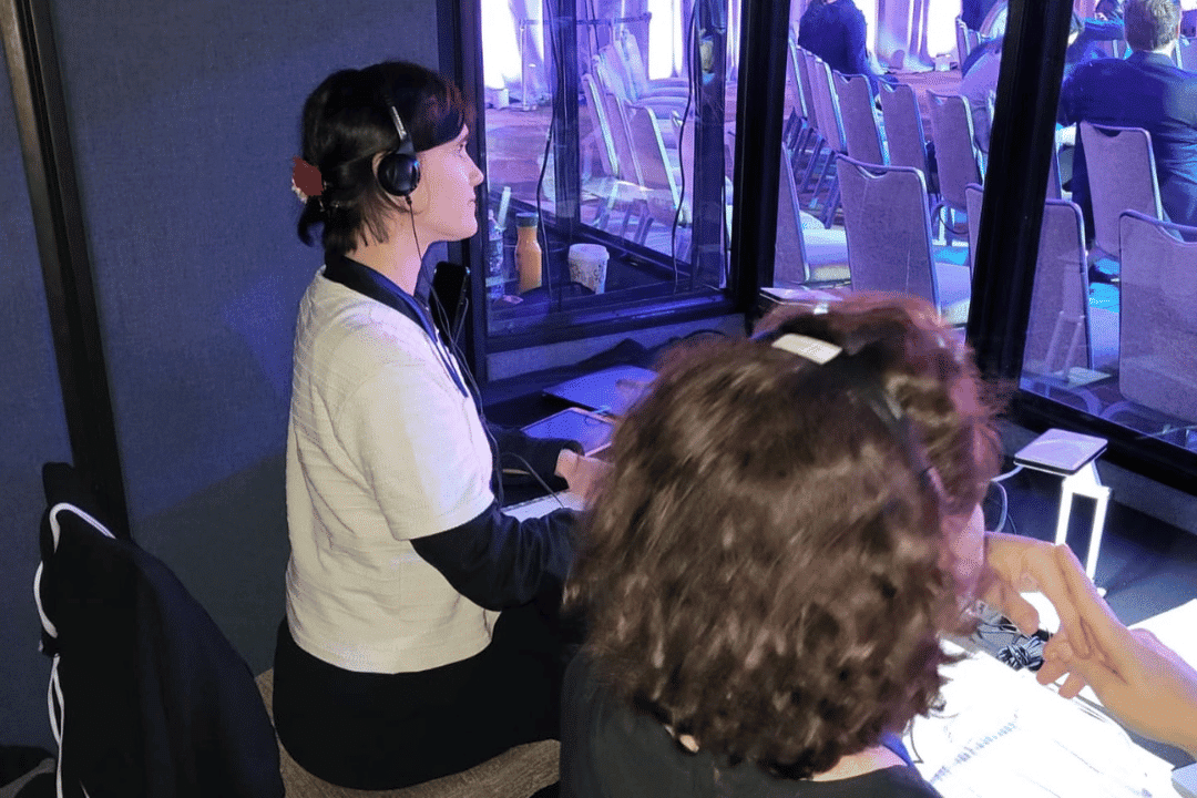 Professional interpreter using headset in a conference booth providing real-time language interpretation during event